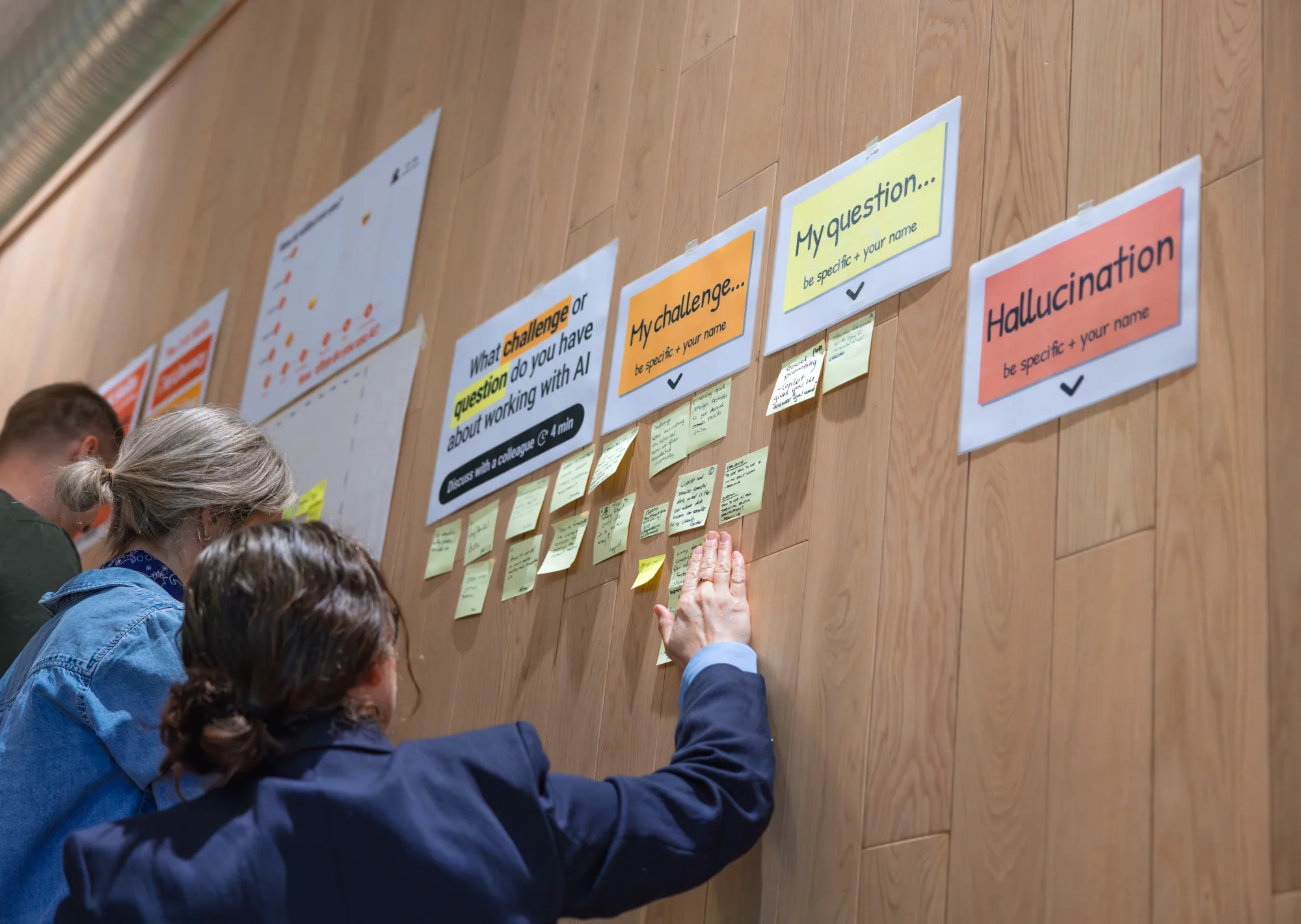 Groep bespreekt een muur vol post-its tijdens een werksessie